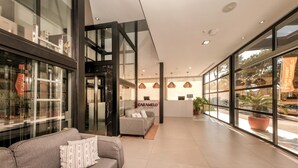 A modern hotel lobby with a sofa, a reception desk, and large windows. - Globales Honolulu (Calvia)