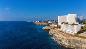A coastal hotel with a view of the sea, featuring a large building with multiple floors and a balcony area. - Globales America (Manacor)