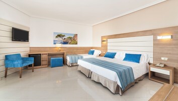 Habitación de hotel con una cama grande, dos mesitas de noche, un escritorio, una silla, un televisor y un cuadro en la pared.