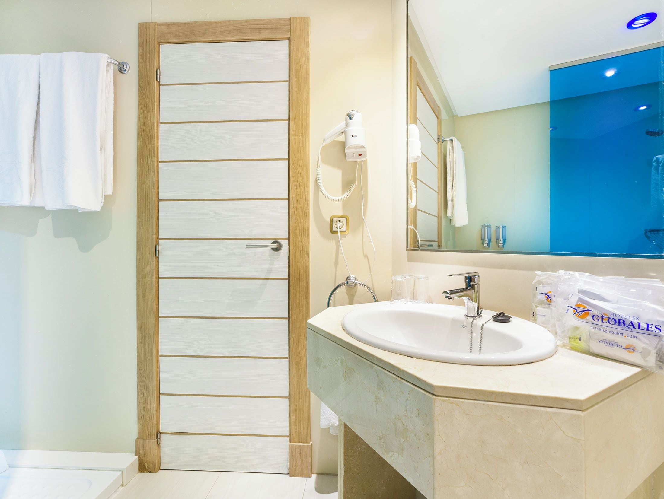 A bathroom with a white sink, a mirror, a towel rack, and toiletries.