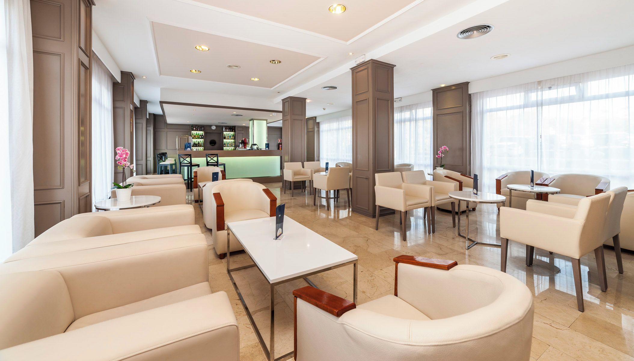 Un vestíbul ampli amb diverses zones d'estar, una recepció i un bar.