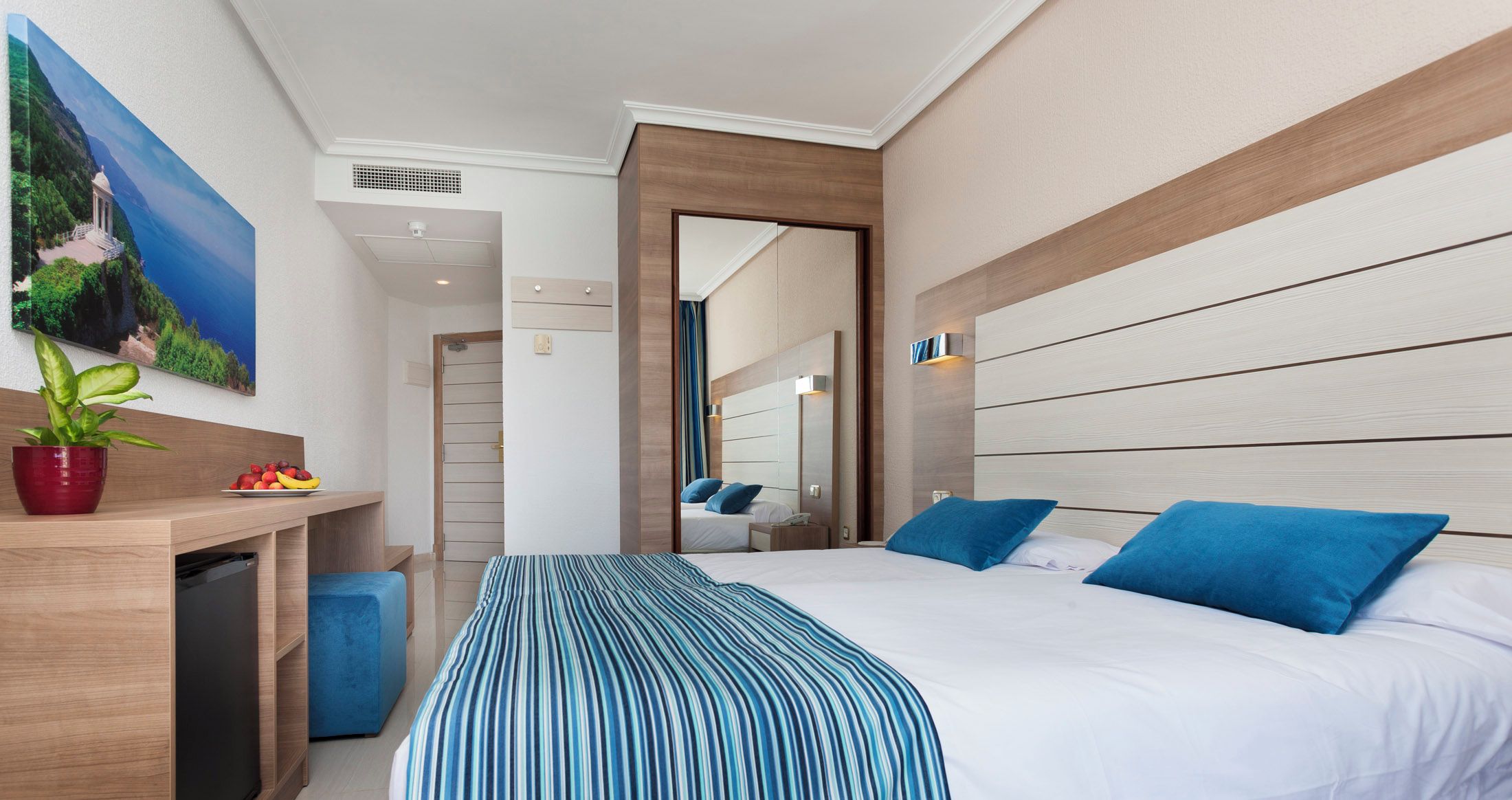 Una habitación de hotel con una cama, una mesita de noche y un cuadro en la pared.