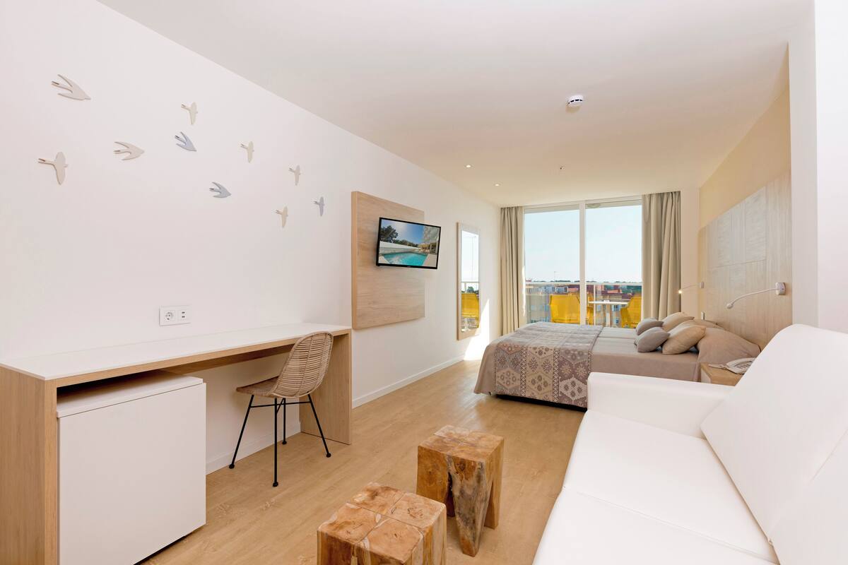Ein modernes Schlafzimmer mit Schreibtisch, Bett und Blick auf die Stadt.