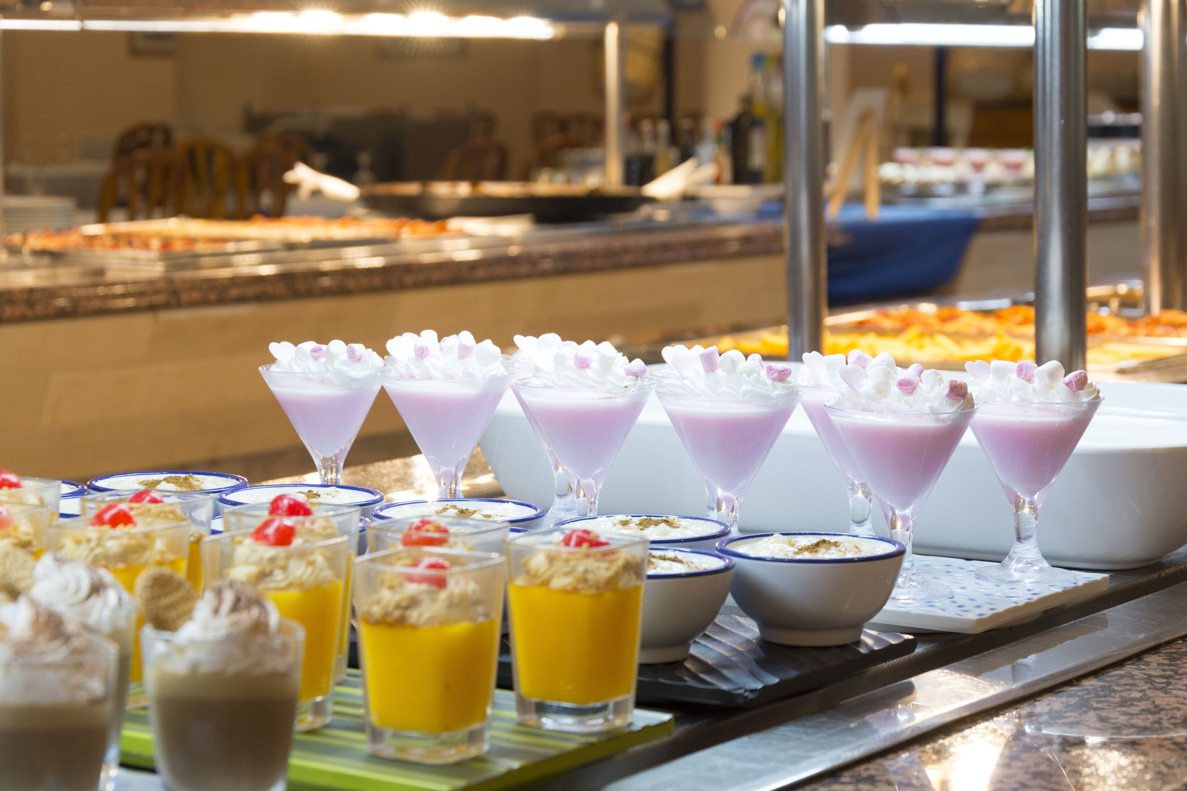 A buffet with various desserts and beverages, including parfaits and fruit cups.