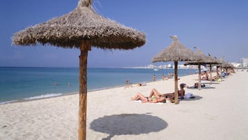 In Strandnähe, weißer Sandstrand, Liegestühle, Sonnenschirme