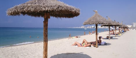 Vlak bij het strand, wit zand, ligstoelen aan het strand, parasols