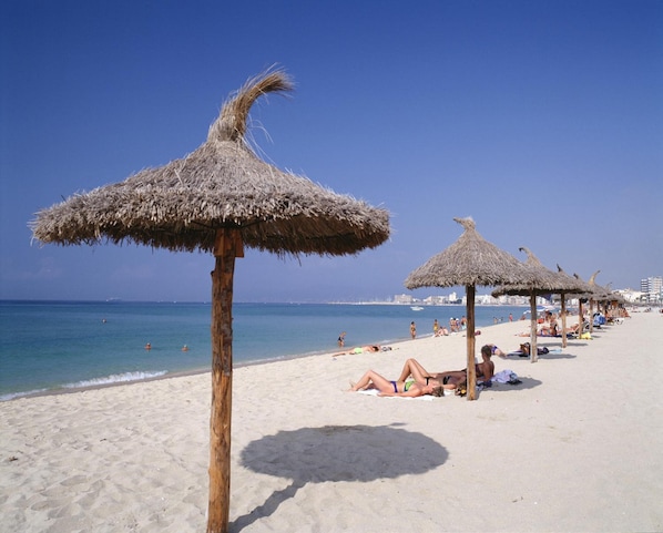 Vlak bij het strand, wit zand, ligstoelen aan het strand, parasols