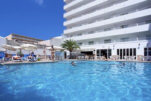 Una piscina al aire libre, sombrillas, tumbonas