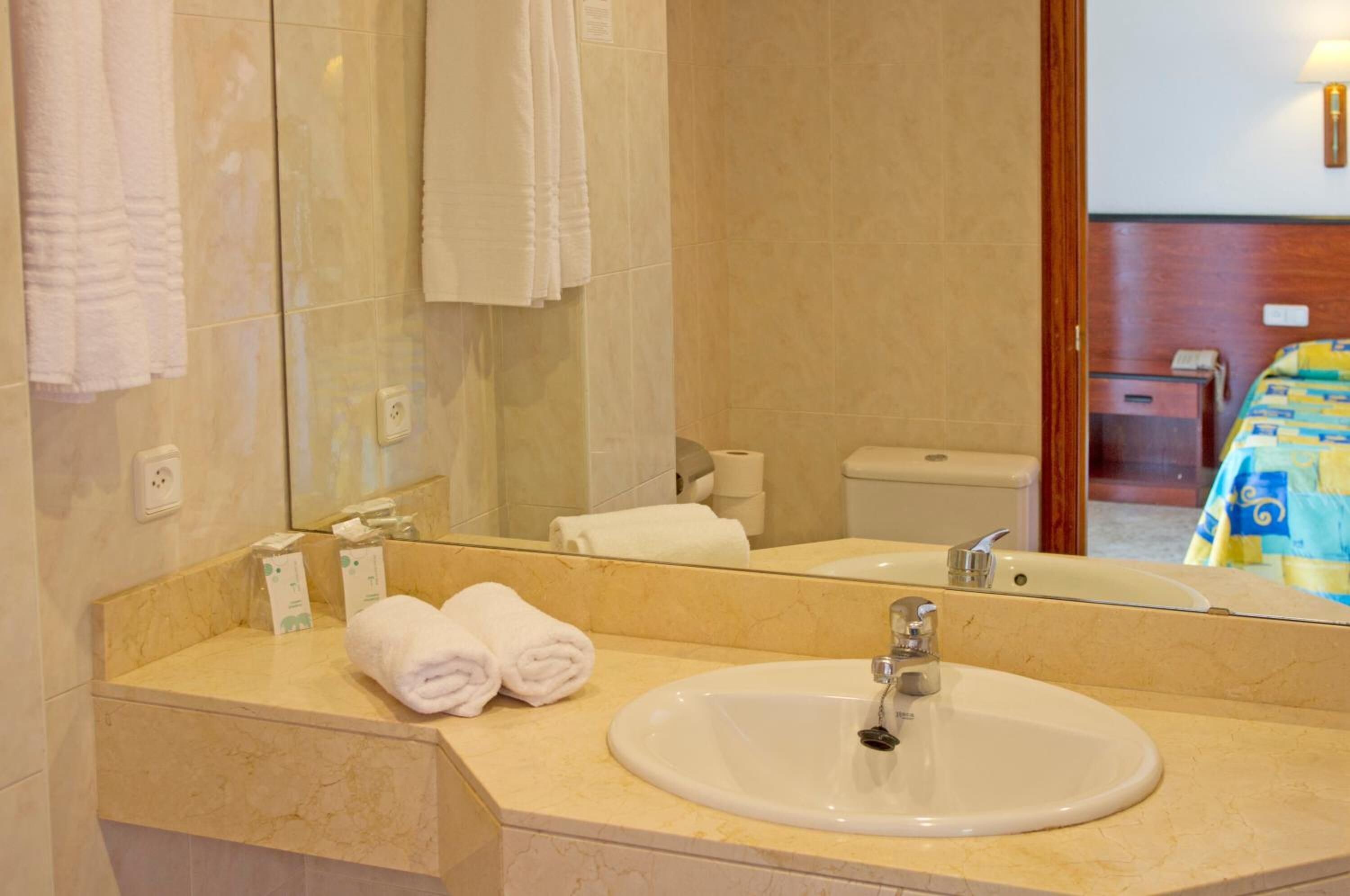 A bathroom with a sink, mirror, and towels.