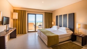 Ein Hotelzimmer mit Bett, Nachttischen, einem Schreibtisch mit Computer, einem Fernseher und einem Balkon mit Blick.