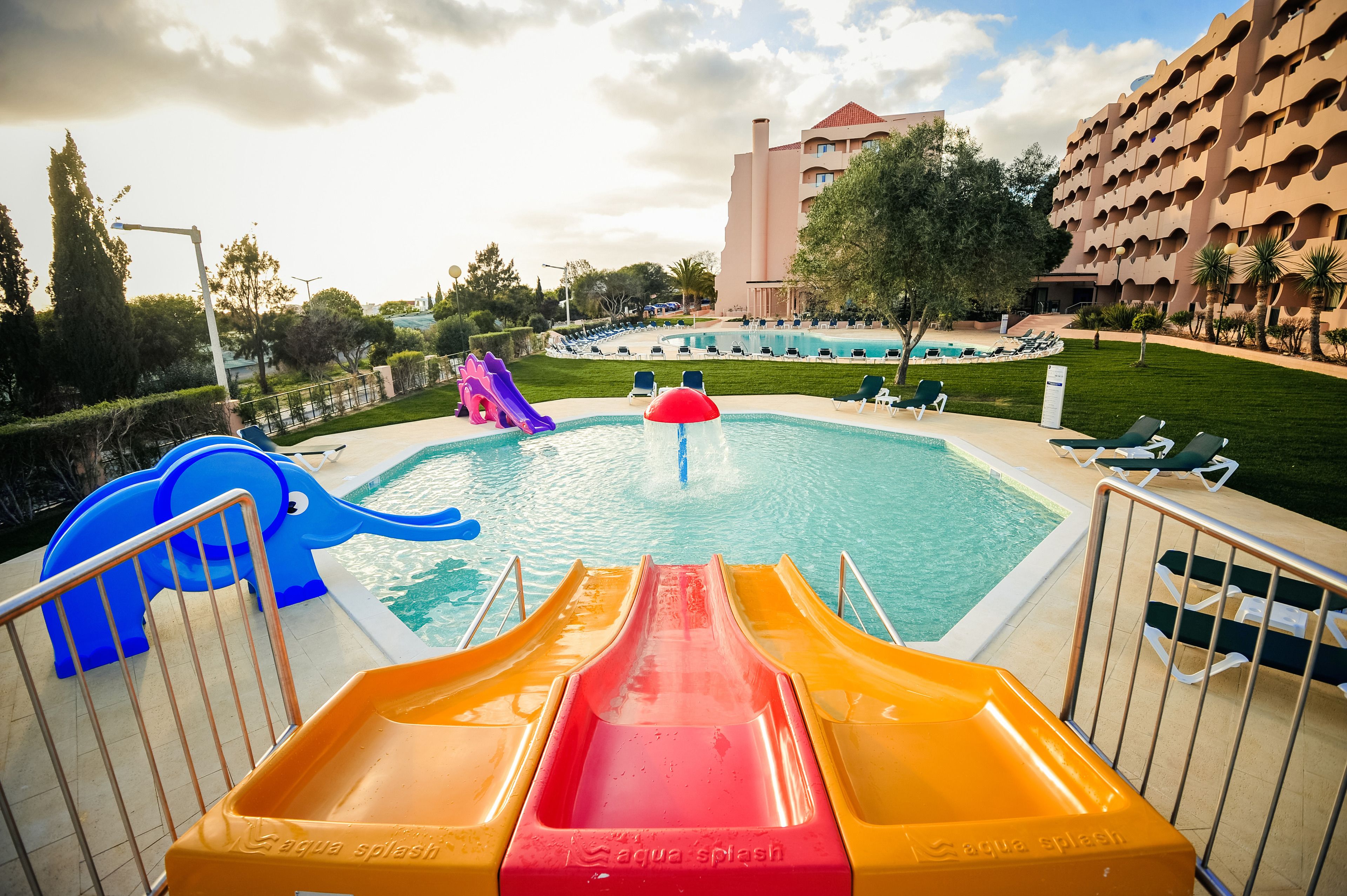 A pool area with slides and a building in the background.
