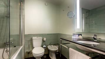 Un baño moderno con bañera, inodoro, bidé y lavabo con espejo superior.