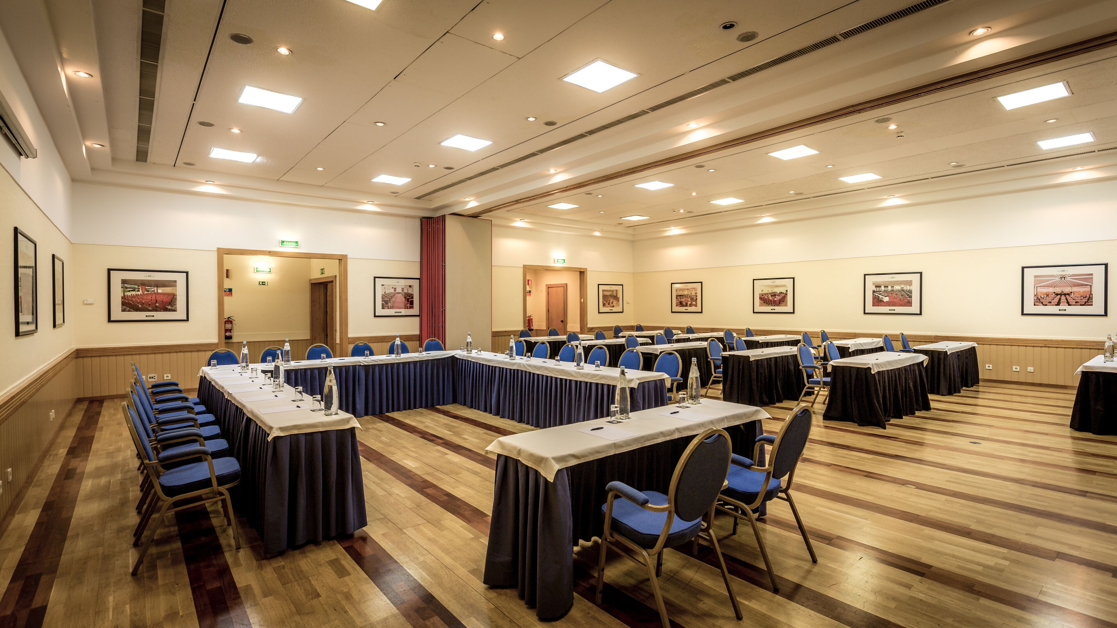 A conference room with long tables, chairs, and framed pictures on the walls.