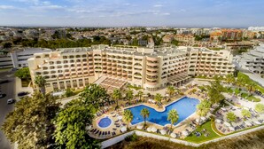 Un hotel con una piscina grande, varios balcones y vistas de la ciudad circundante.