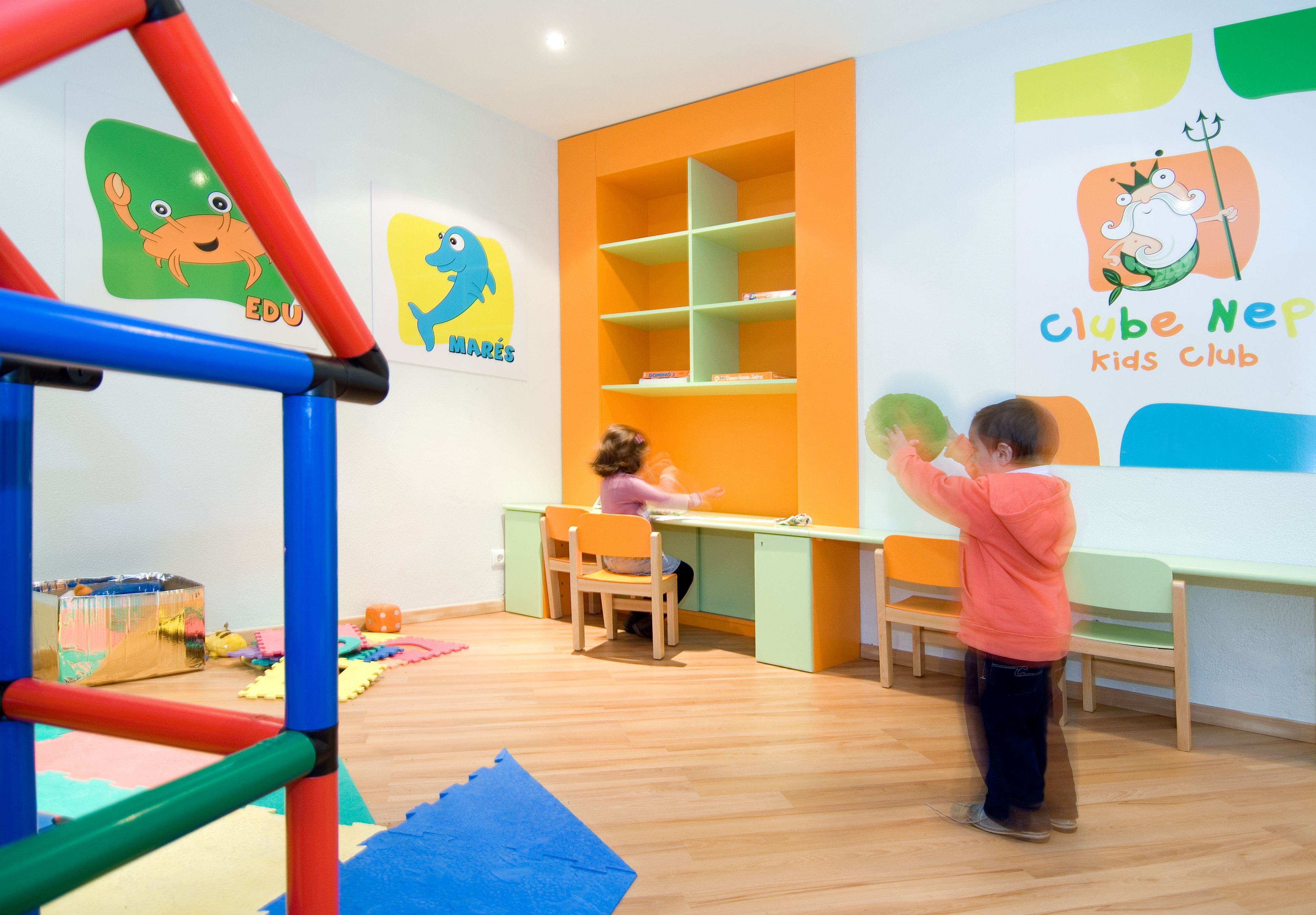 A children's play area with a climbing structure, a desk, and chairs.