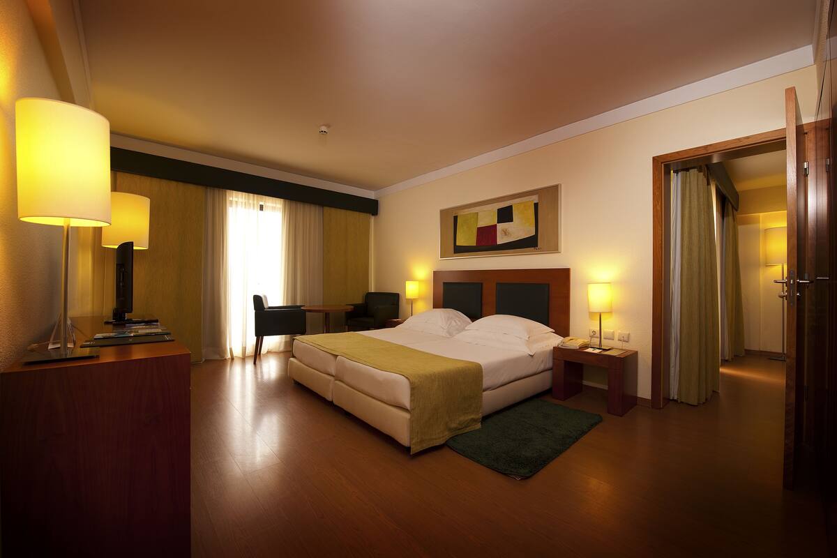 A hotel room with a bed, bedside tables, a desk, and a chair.