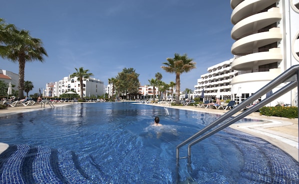 Una piscina techada, una piscina al aire libre, sombrillas