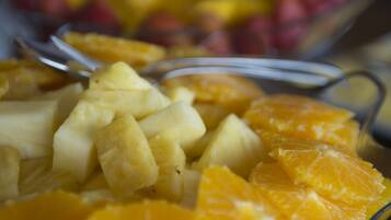 Un tazón de frutas con trozos de piña y gajos de naranja.
