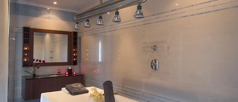 A modern bathroom with a large mirror, a vanity with a towel and flowers, and a shower area.