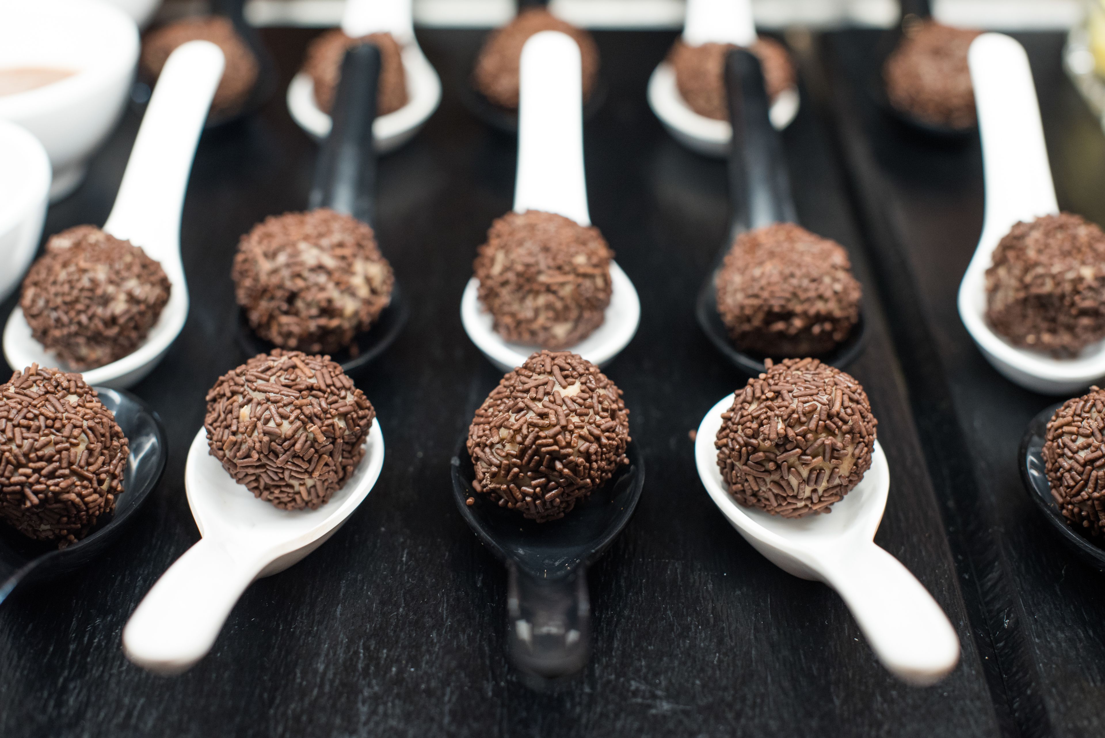A tray of chocolate truffles on spoons.