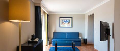 A modern living room with a blue sofa, a coffee table, a floor lamp, and a television.