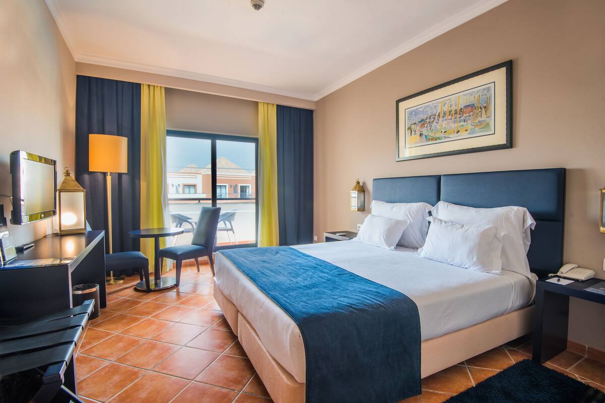 Une chambre d’hôtel équipée d’un lit, d’un bureau, d’une chaise et offrant une vue sur le paysage urbain.