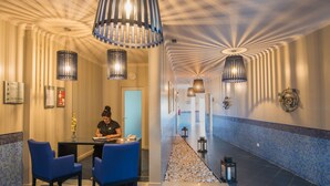 A hotel lobby with a reception desk, blue chairs, and a decorative ceiling.