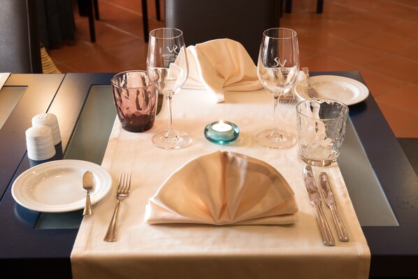 Una mesa de comedor bien dispuesta, con platos, cubiertos y copas.