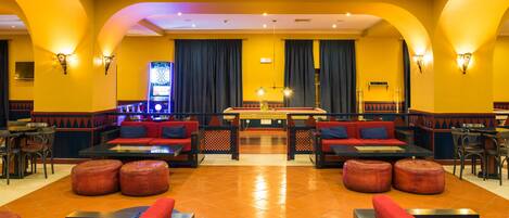 A spacious lobby with multiple seating areas, a pool table, and a dartboard.