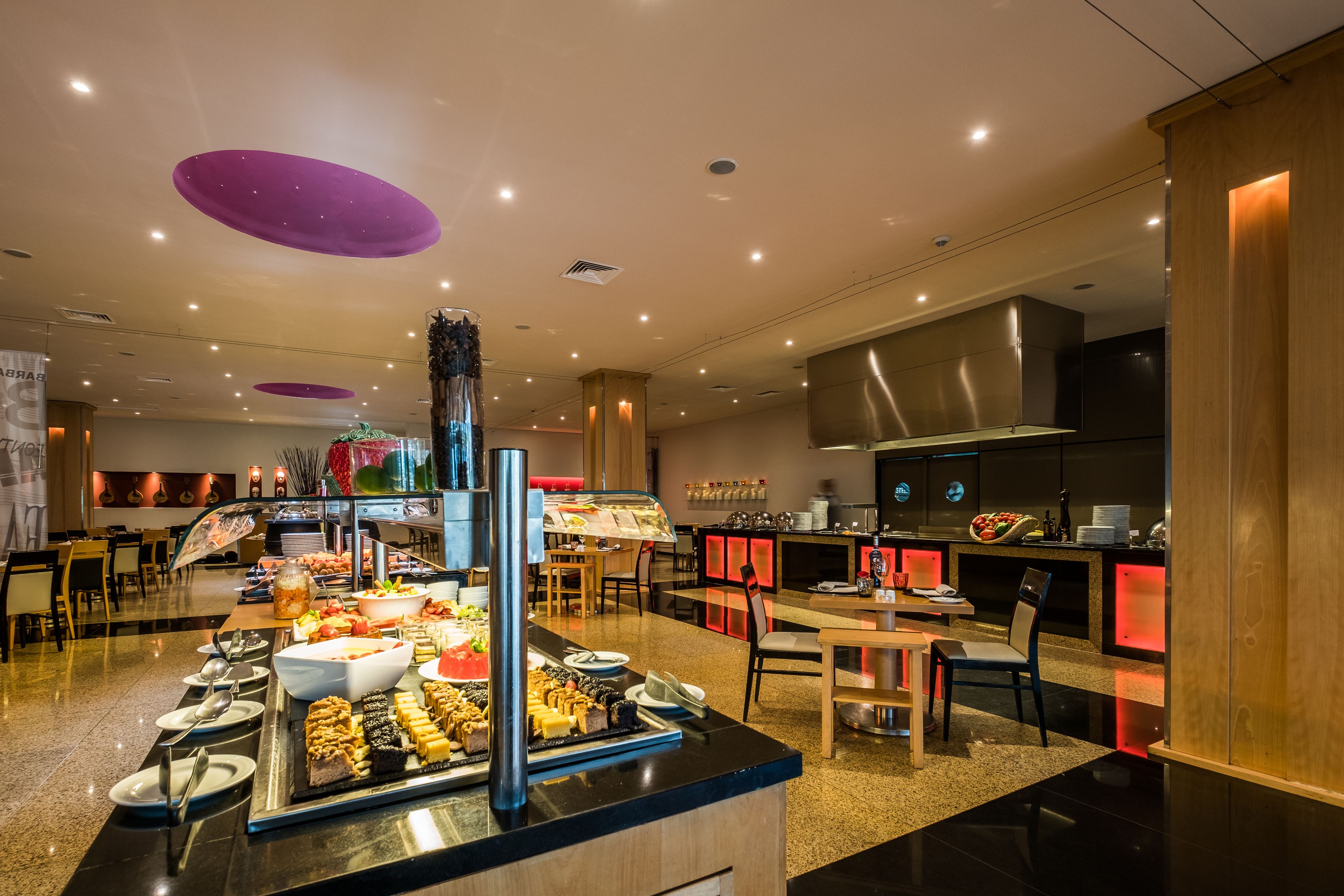 A buffet area with various food items and a seating area with tables and chairs.