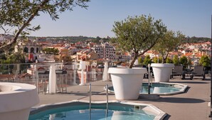 A rooftop pool area with lounge chairs and a view of a cityscape. - Vila Gale Opera Hotel (Lisbon)