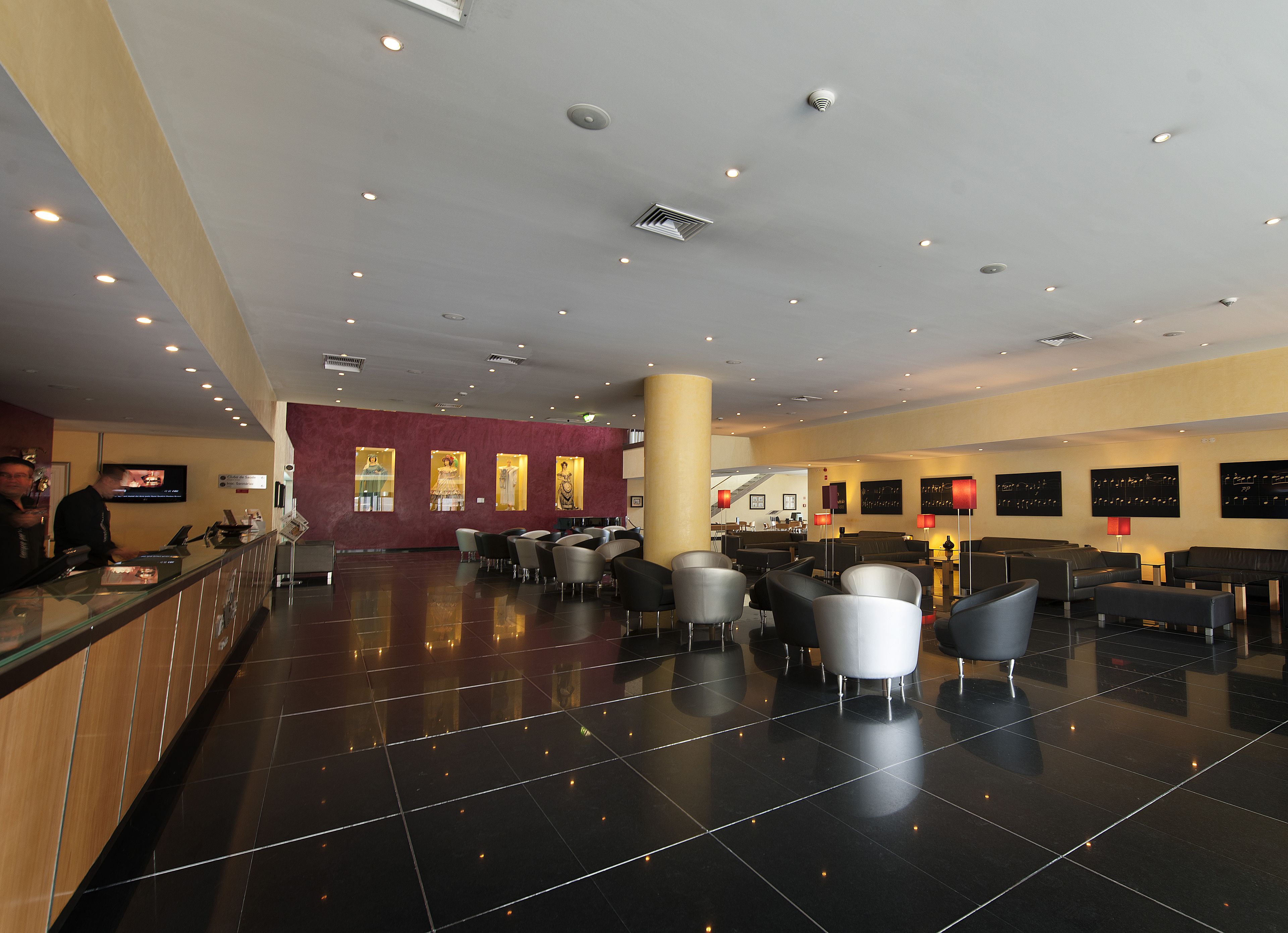 A spacious lobby with a reception desk, seating area, and a staircase leading to upper floors.