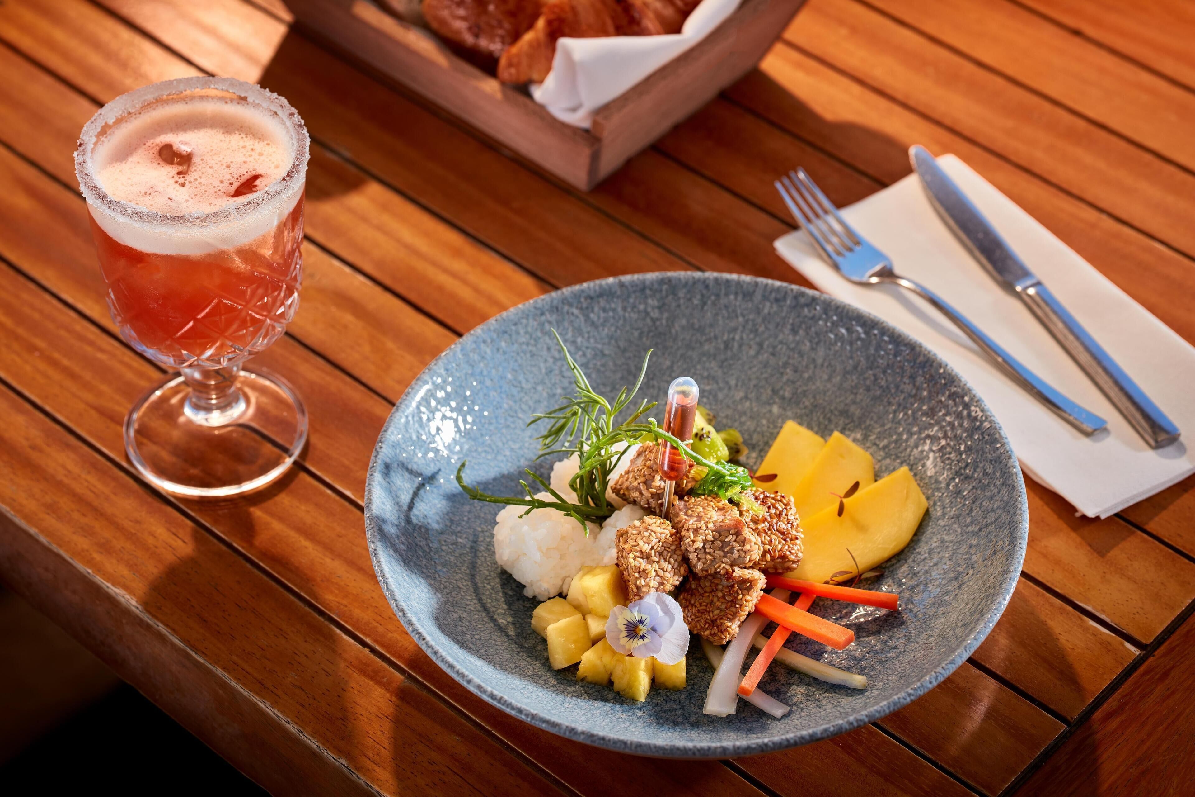 Ein Teller Essen mit Reis, Gemüse und einem Getränk auf einer Holztischplatte.