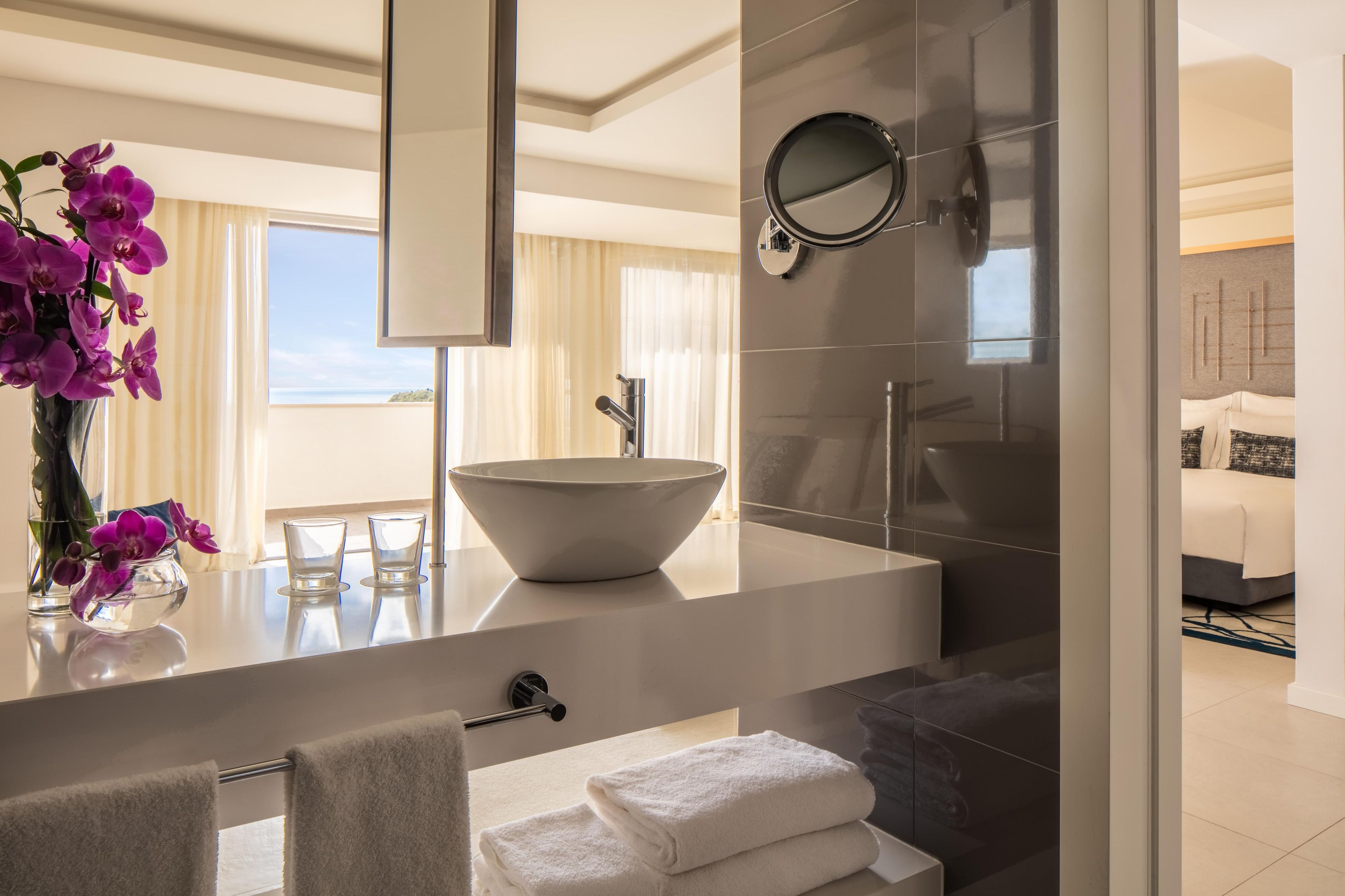 Un baño moderno con un lavabo blanco grande, un espejo y vistas al mar.