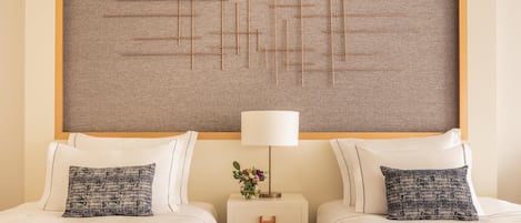 A hotel room with two beds, a nightstand with a lamp, and a decorative wall panel.