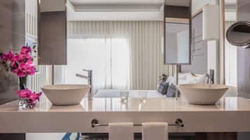 A modern bathroom with two large sinks, a mirror, and a vase of pink flowers.