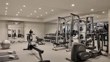 Un gimnasio moderno con diversos equipos de ejercicio, incluyendo cintas de correr, máquinas de pesas y pesas libres.