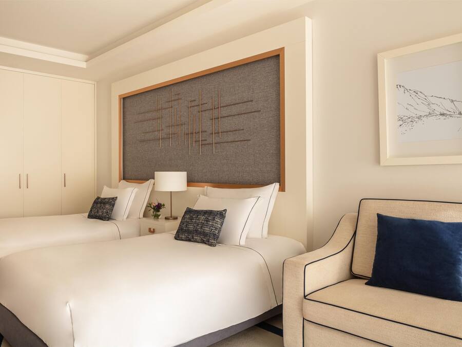 A hotel room with two beds, a sofa, a large artwork on the wall, and a framed picture.