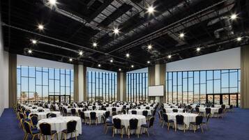 A large conference room with round tables and chairs, large windows, and a city view.