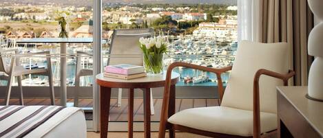 Une chambre d’hôtel avec un balcon donnant sur un port de plaisance et la ville.