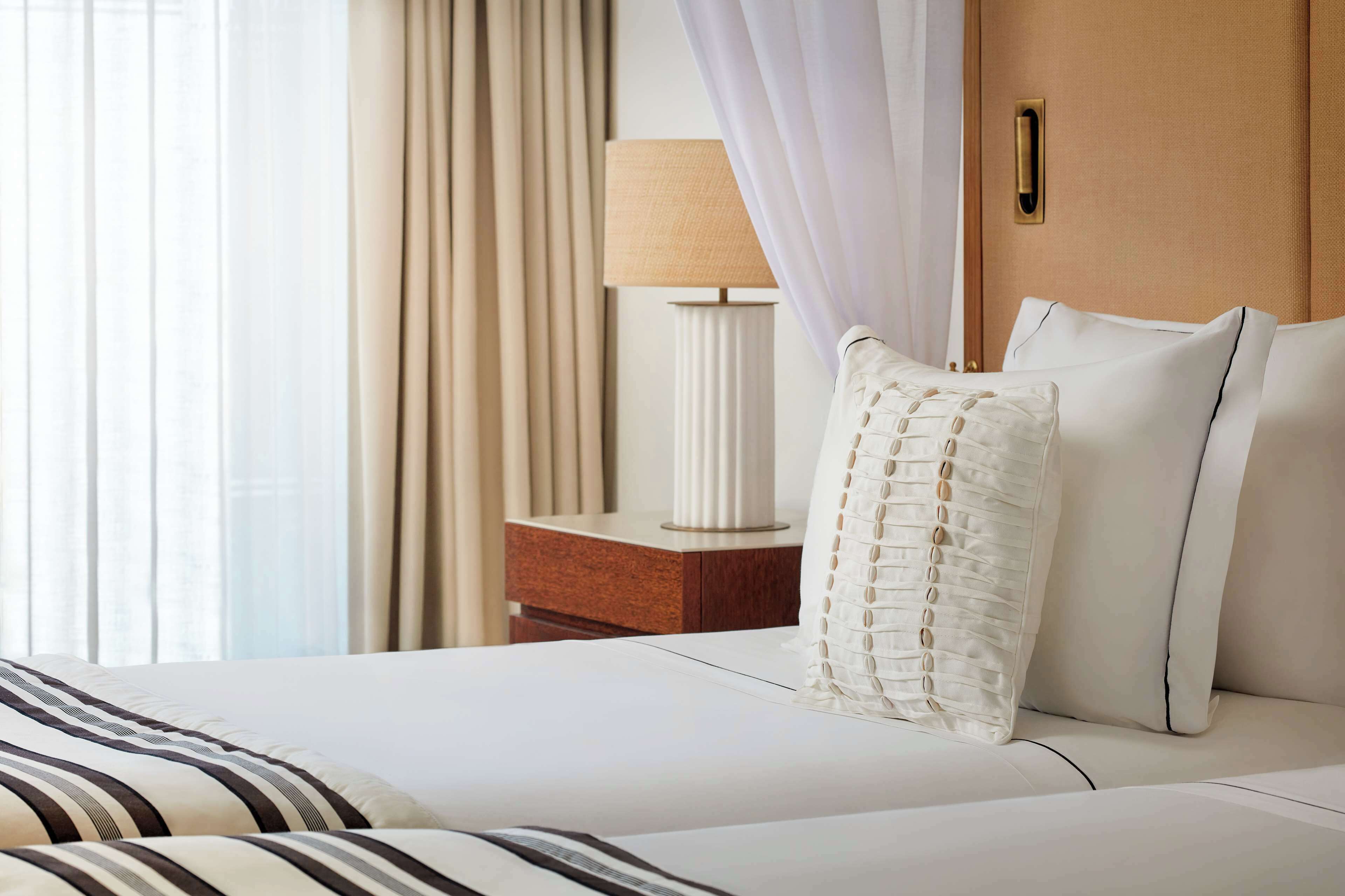 A hotel room with a bed, a nightstand, a lamp, and curtains.