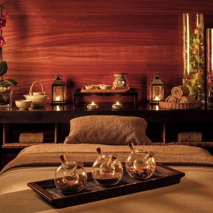 A spa room with a massage table, candles, a tray of teapots, and decorative items.