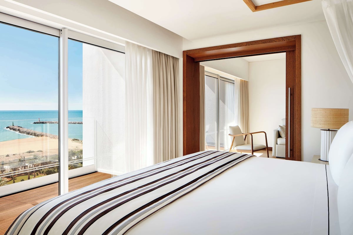 Een hotelkamer met een groot bed, uitzicht op het strand en een houten vloer.