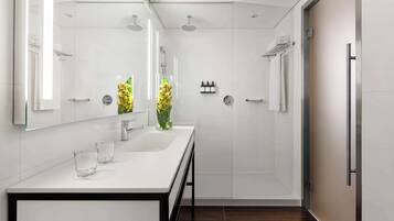 Un baño moderno con tocador blanco, cabina de ducha de vidrio y un espejo grande.