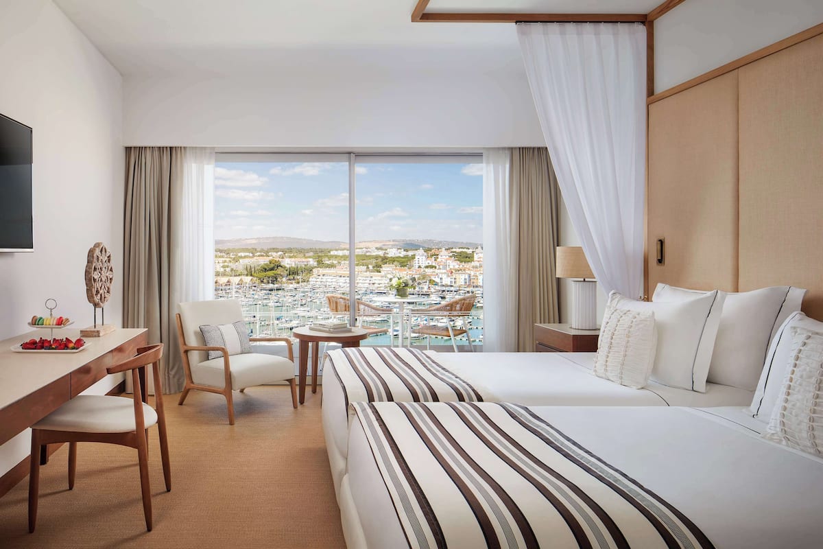 Een hotelkamer met een groot bed, een bureau met stoel, een kleine tafel en een televisie.