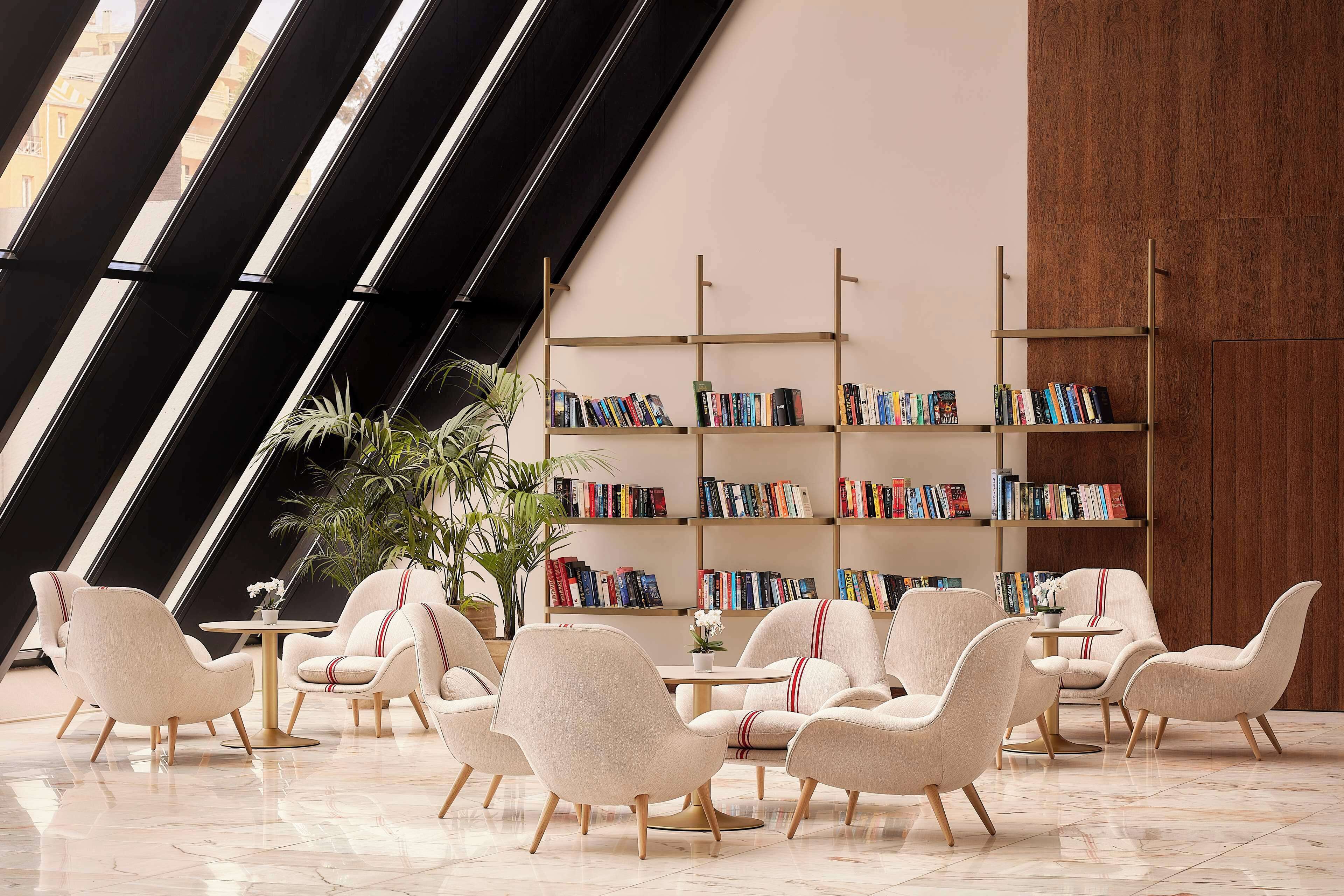 A modern lounge area with plush chairs, a coffee table, and bookshelves filled with books.