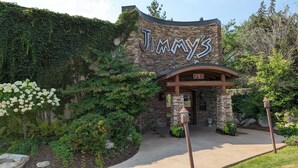 A stone building with a sign reading "Jim's" and an "OPEN" sign above the entrance. - Walker Hotel (Walker)