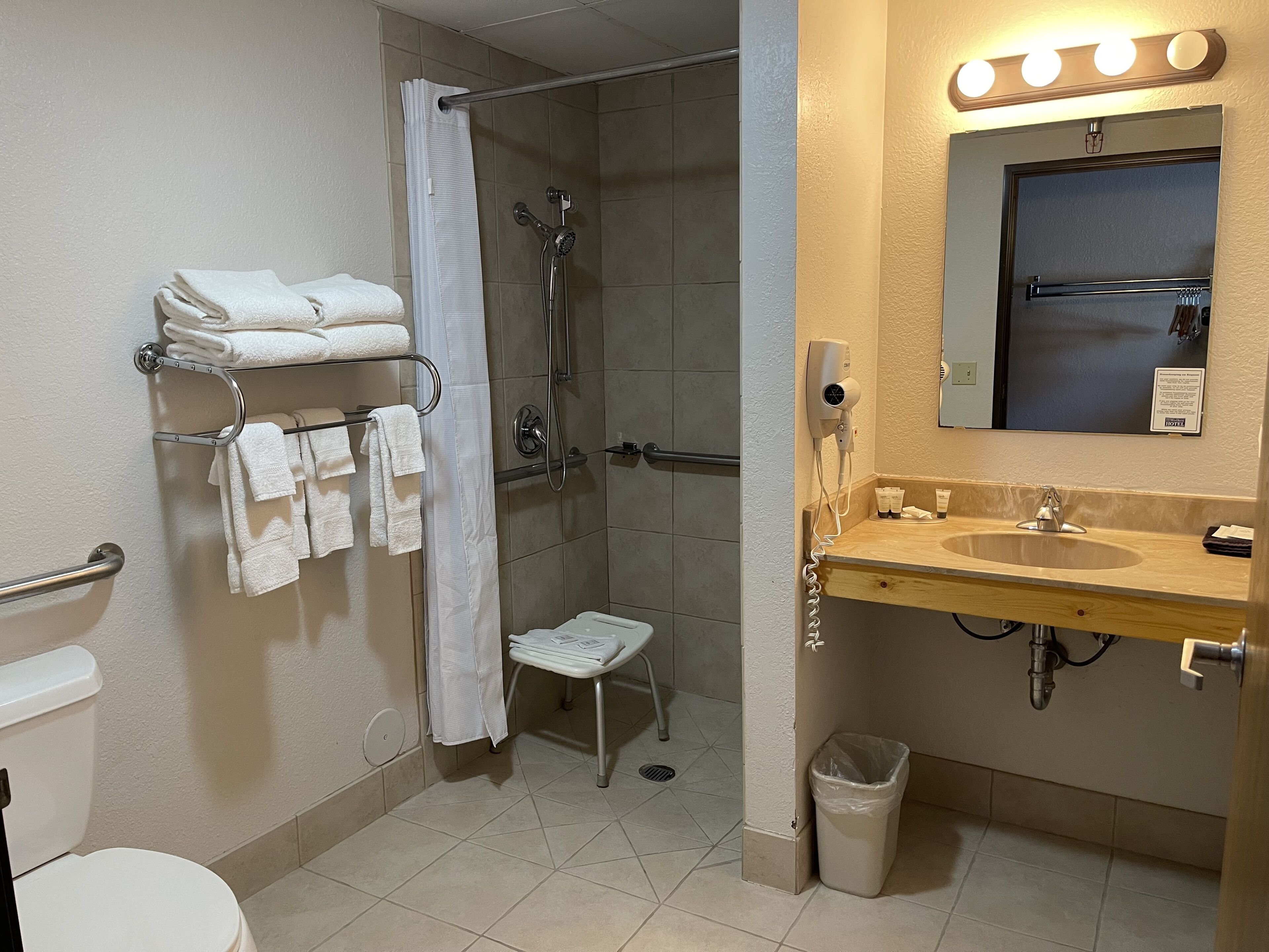 A bathroom with a shower, toilet, sink, and towel rack.