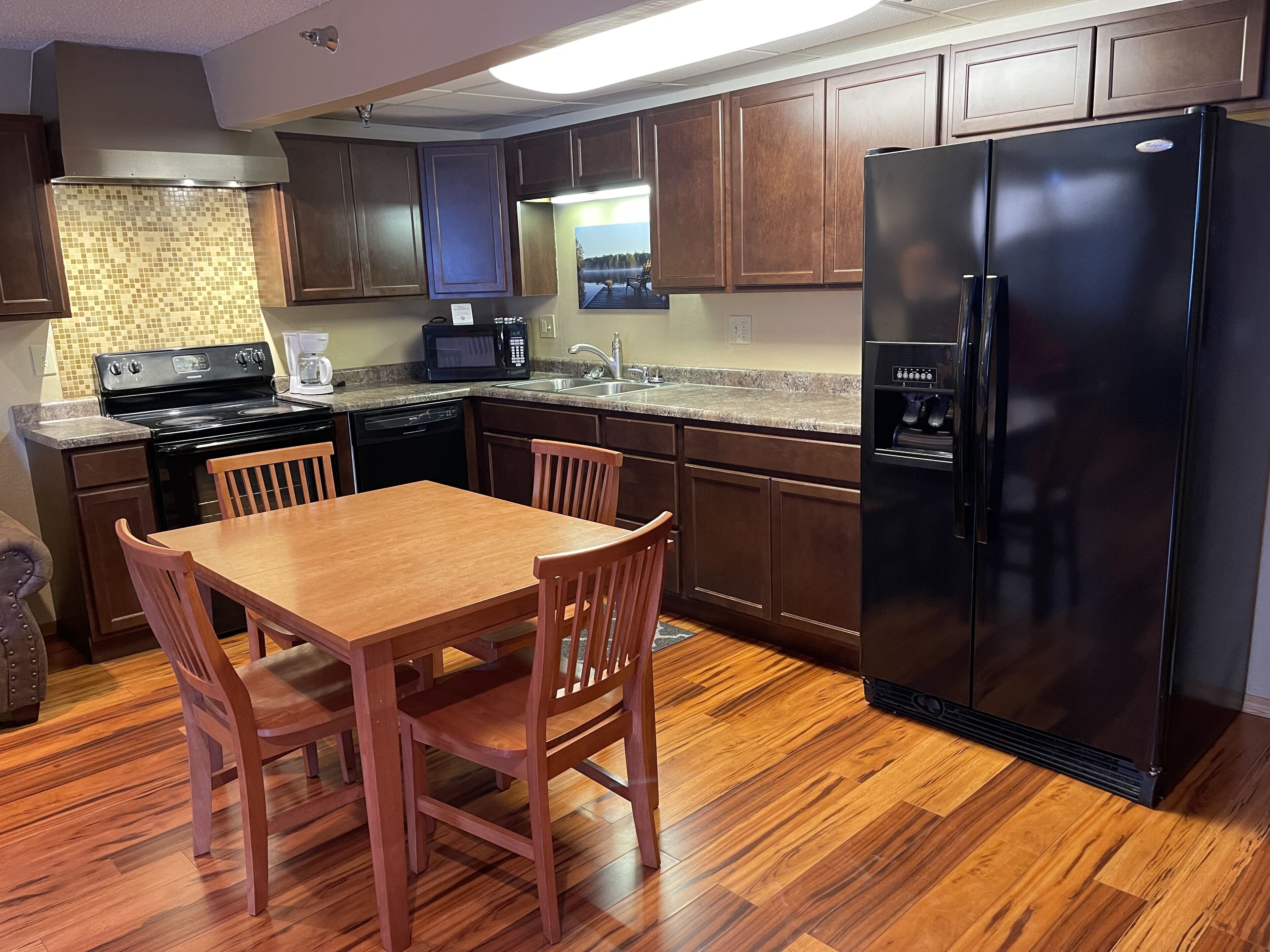 A modern kitchen with wooden cabinets, a black refrigerator, a microwave, and a dishwasher.
