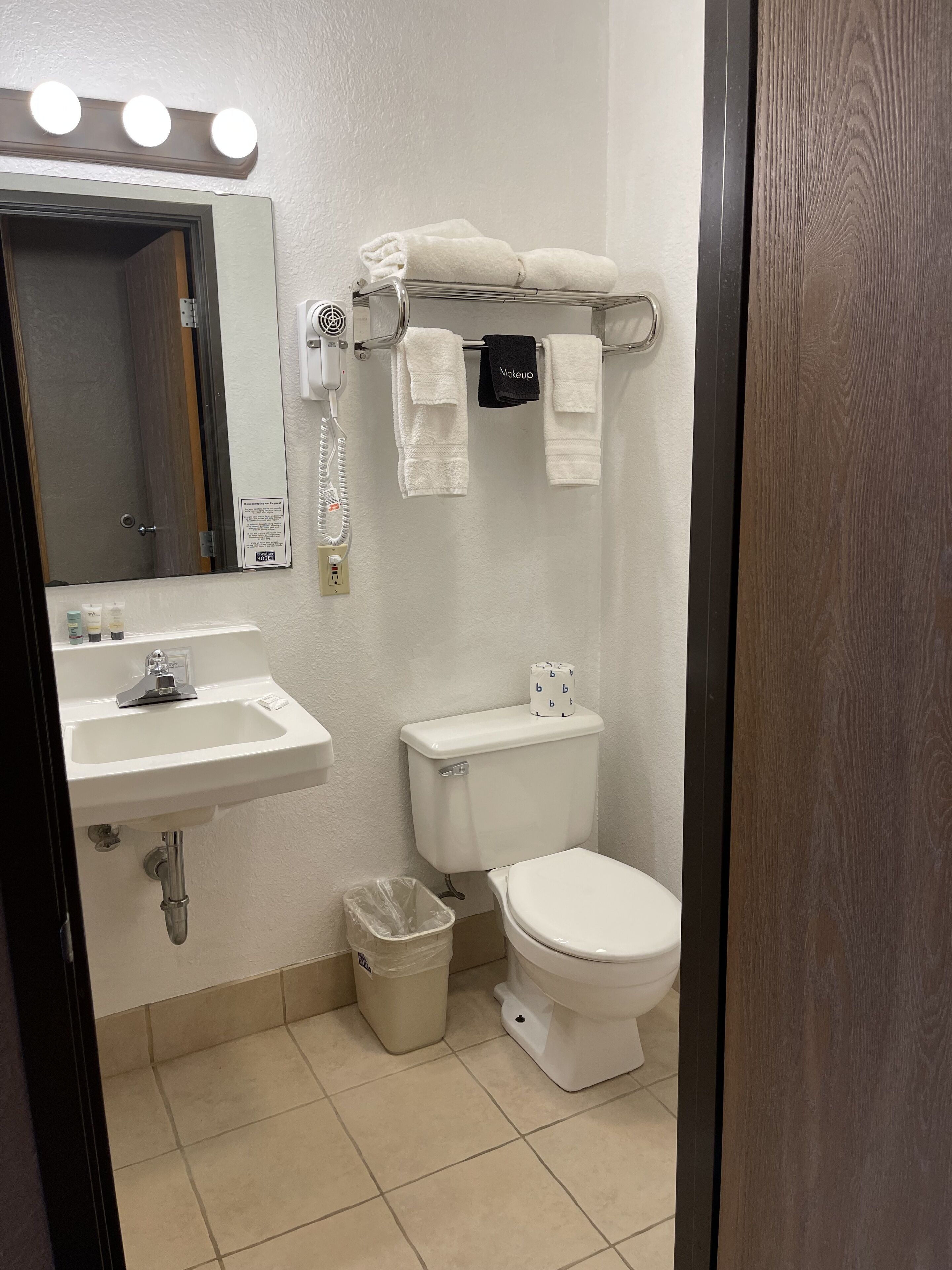 Ein Badezimmer mit Waschbecken, Spiegel, Handtuchhalter, Toilette und Mülleimer.
